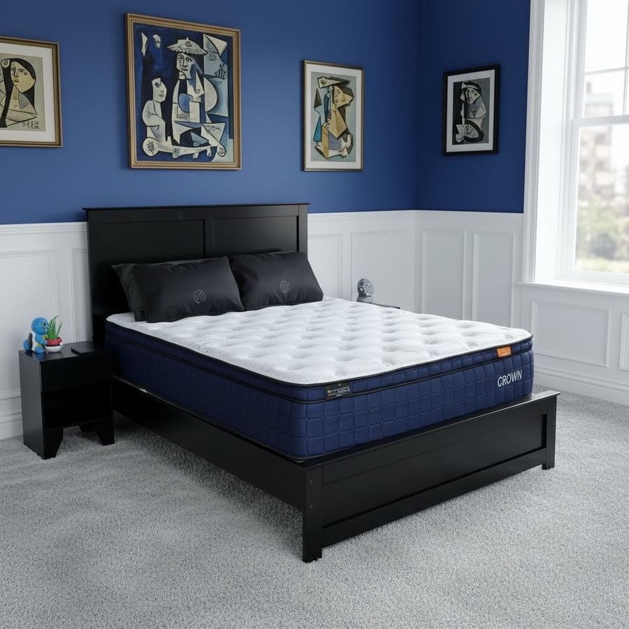 Kingdom Royalty Pillow Top mattress with a white quilted top and navy sides on a black bed